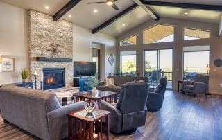 Spacious living room with hardwood floors, stone fireplace, ample natural light, and cozy atmosphere in Show Low, AZ.