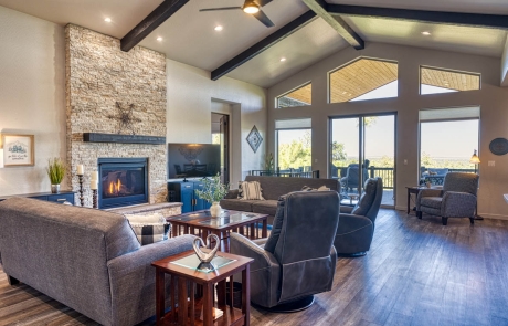 Spacious living room with hardwood floors, stone fireplace, ample natural light, and cozy atmosphere in Show Low, AZ.