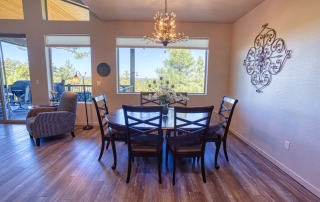 Bright dining room with wooden flooring, wall art, and large windows offering a scenic view. For sale in Show Low, AZ.