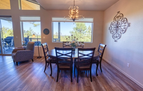 Bright dining room with wooden flooring, wall art, and large windows offering a scenic view. For sale in Show Low, AZ.