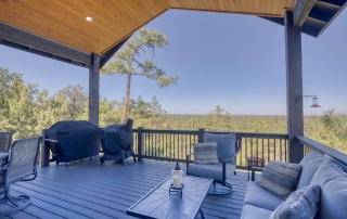 Spacious outdoor deck with wooden flooring, surrounded by lush trees and open sky. Tranquil setting in Show Low, Arizona.