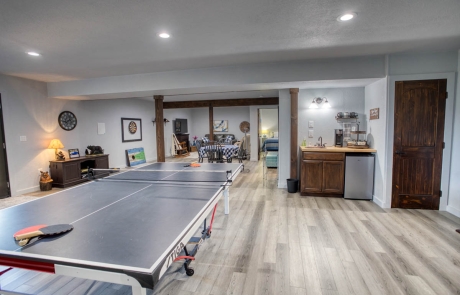 Spacious recreational room with laminate flooring, built-in storage, warm lighting. For sale in Show Low, Arizona.