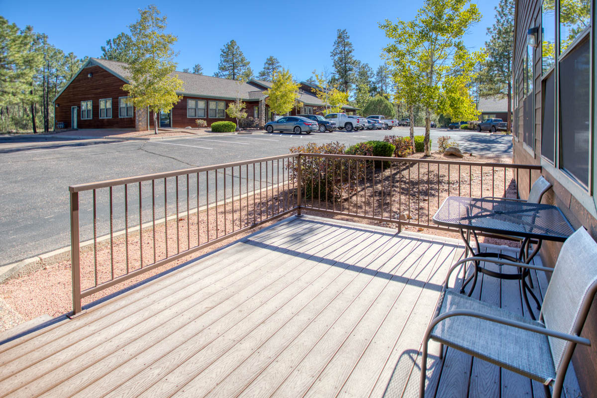 Showlow Office Buildings for Sale (14) Outdoor deck with wooden flooring and railing, overlooking a parking area with trees, for sale in Show Low, Arizona.