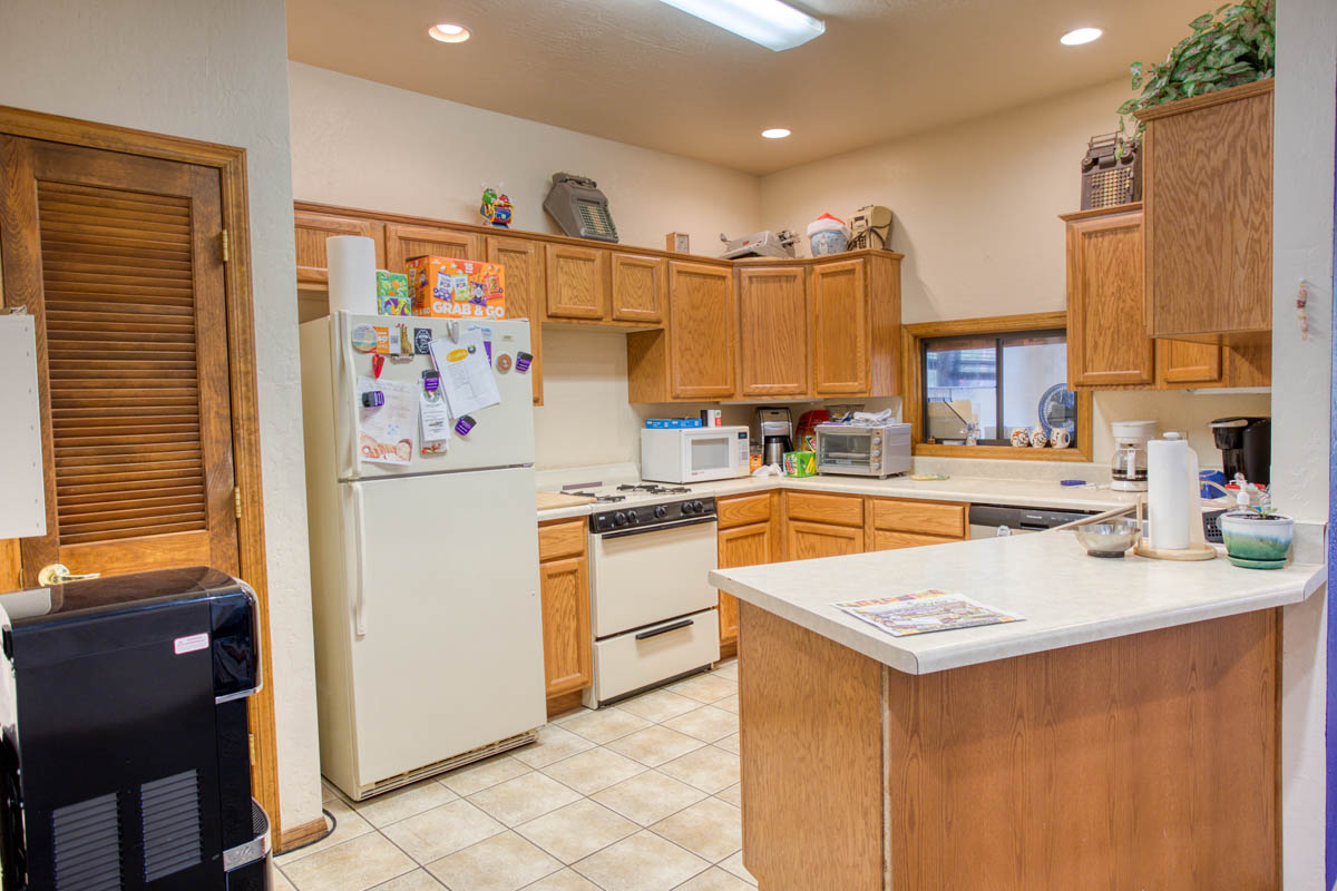 Showlow Office Buildings for Sale (16) Cozy kitchen with tiled flooring, ample wooden cabinetry, and a warm, inviting atmosphere for sale in Show Low, Arizona.
