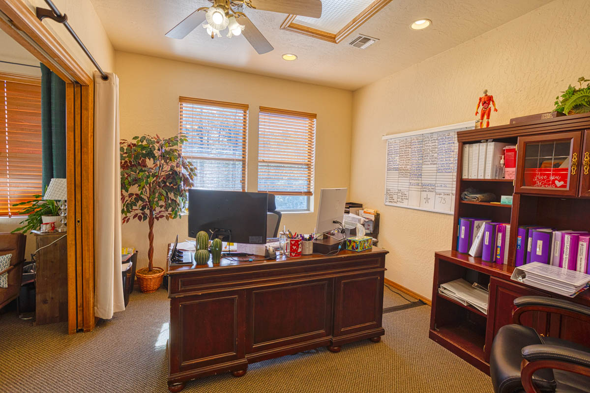 Showlow Office Buildings for Sale (4) Home office with carpet flooring, organized shelving, ample light from windows. Cozy workspace for sale in Show Low, Arizona.